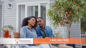a young couple sits next to a peach tree