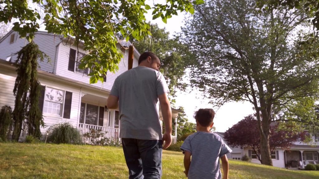 man and boy walk towards house