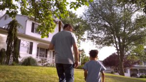 man and boy walk towards house