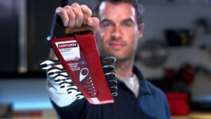man holds up wrenches