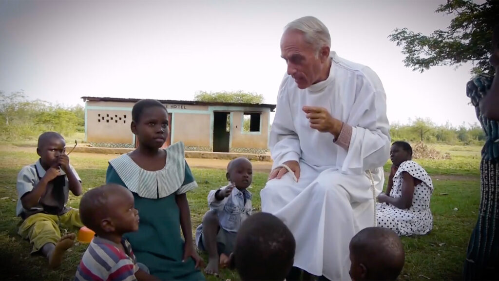 priest sits and talks with african kids